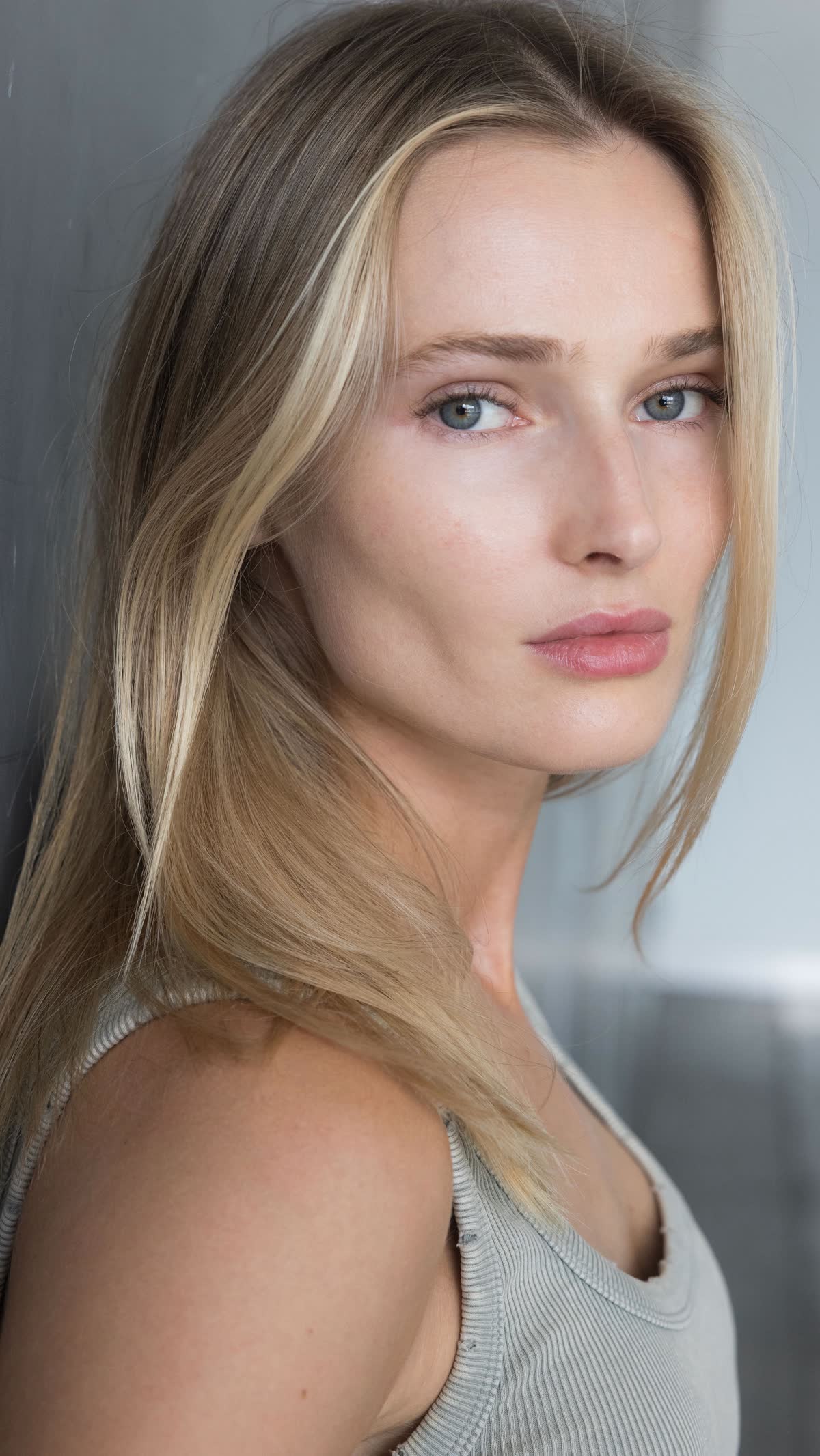 Anastasiia Koval photographed close in soft daylight, blue eyes level with the lens, hair falling across her shoulder.
