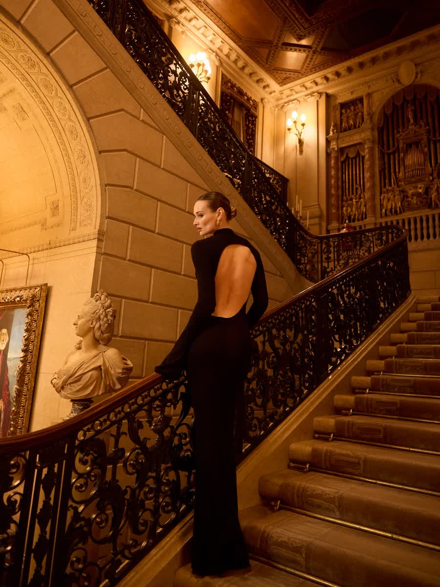 Anastasiia Koval in a black gown on a grand marble staircase.