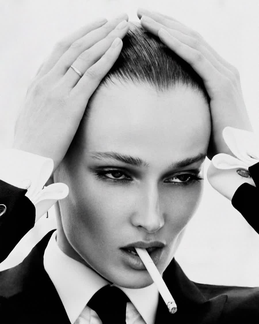Anastasiia Koval in black and white, white gloves lifting her hair, a cigarette between her lips.