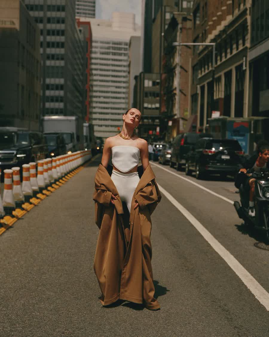 Anastasiia Koval in a long camel coat on an empty city road.