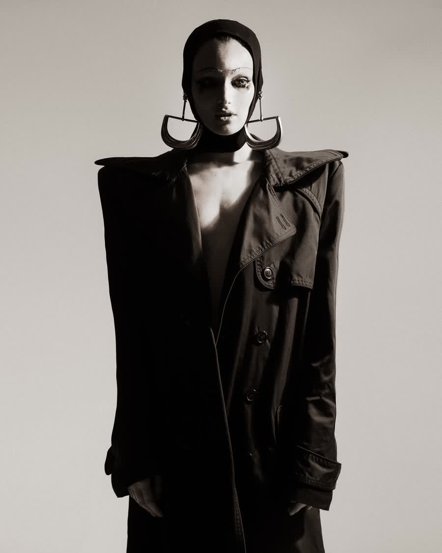 Anastasiia Koval in black tailoring against a warm concrete wall, photographed in black and white.